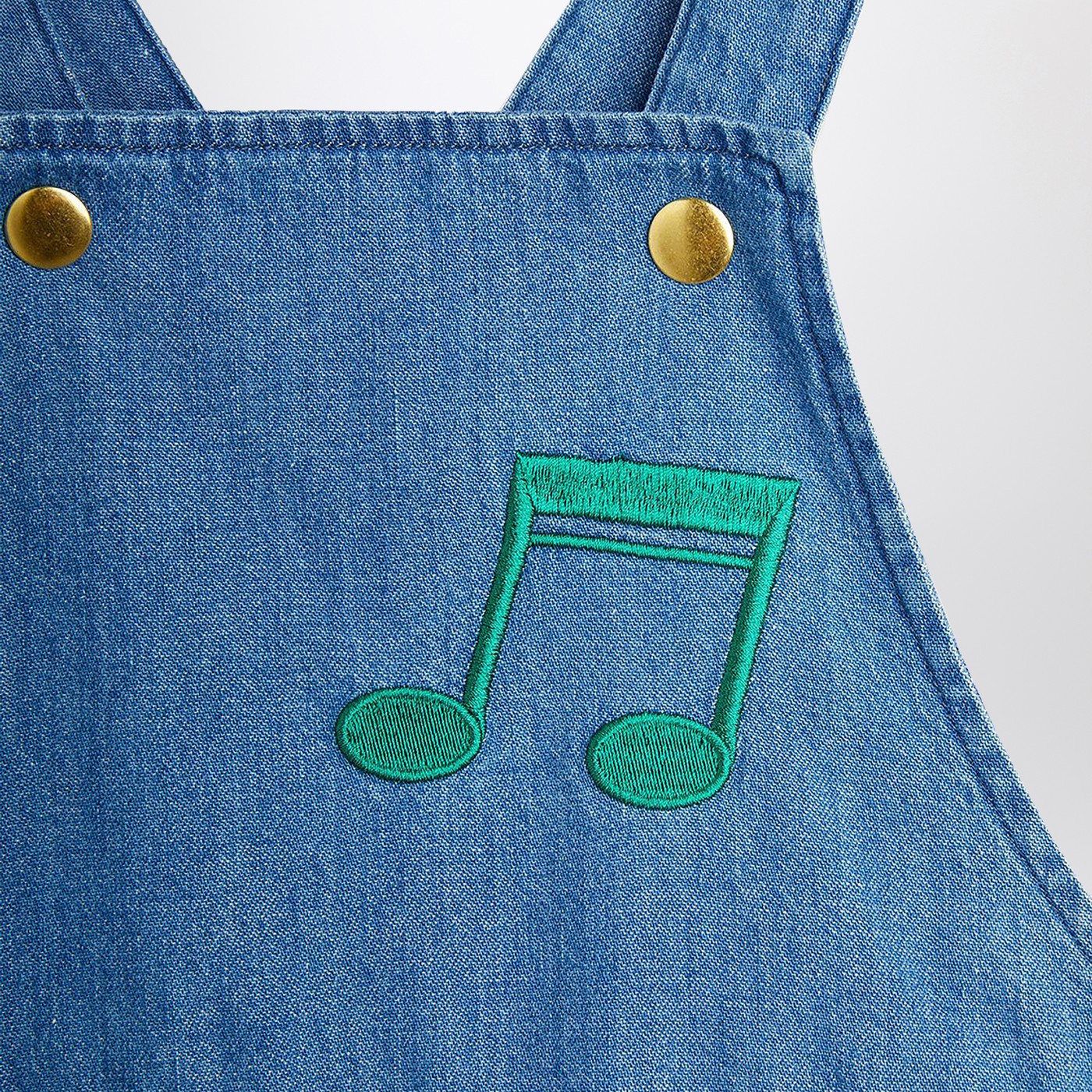 Salopette azzurra in denim con note musicali
