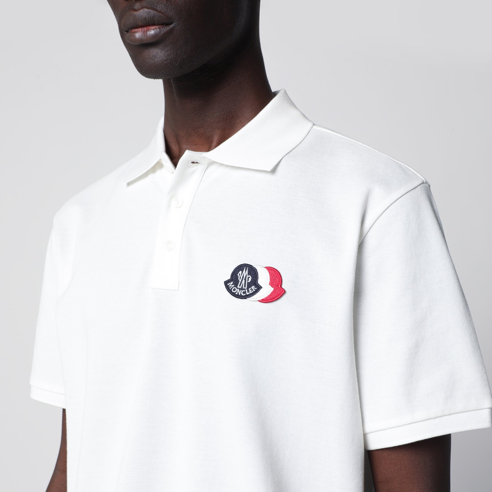 Polo bianca in cotone con patch tre stemmi logo